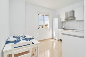 A modern kitchen with white cabinets, a built-in oven, and a window overlooking a cityscape.