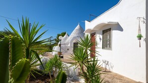 Un bâtiment blanc surmonté d’un toit conique, entouré de cactus et se dressant sous un ciel d’un bleu limpide.