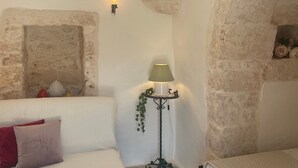 Une pièce avec un canapé blanc, une petite table avec une lampe et un lit.