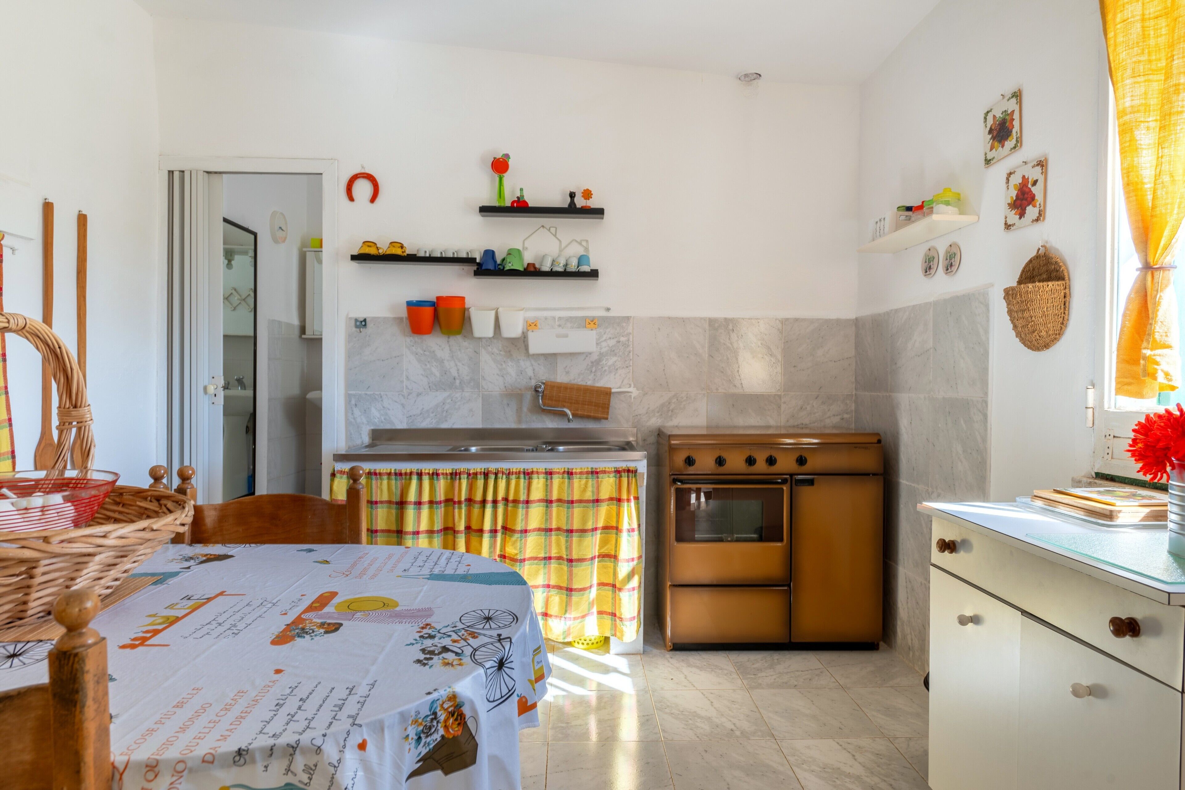 Una cucina con piano cottura, forno e scaffali pieni di utensili.
