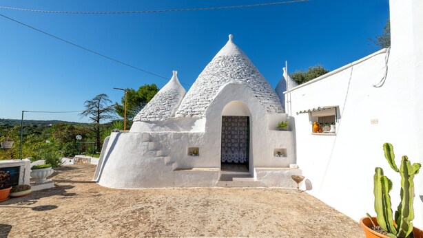 Un bâtiment blanc avec un toit conique, une porte et une petite fenêtre.