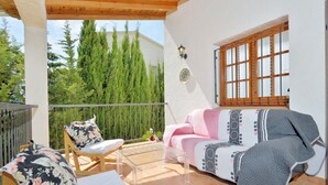 A balcony with a wooden chair, a sofa, and a glass table. - Holiday Home 'Chalet Independiente Costa Daurada' with Private Garden, Balcony and Air Conditioning (Roda de Berà)