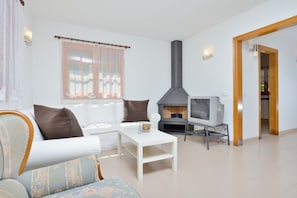 A living room with a white sofa, a coffee table, a fireplace, and a television.