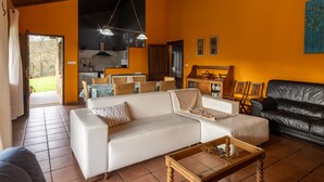 En stue med sofa, sofabord og sort lædersofa. Der er et køkkenområde med spisebord og stole.