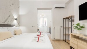 Una habitación de hotel moderna con una cama grande, una mesita de noche, un armario y un televisor fijado a la pared.