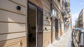 Un edificio con una puerta abierta, un letrero de estacionamiento y un automóvil estacionado.