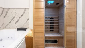 Un baño con pared de mármol, tocador de madera, bañera y cabina de ducha.
