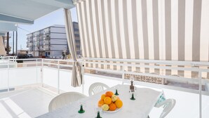Un balcon avec une table blanche, des chaises et une assiette d’oranges.