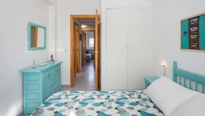 Une chambre à coucher comprenant un lit, une commode, un miroir et une porte donnant sur une autre pièce.