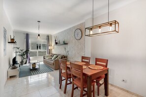 A modern living room with a dining area, a sofa, a coffee table, and a wall clock.