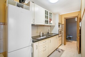 A kitchen with white cabinets, a black countertop, and a microwave.