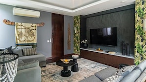 A modern living room with a grey sofa, a coffee table, and a flat-screen TV mounted on a dark wall. - De Prestigio Villa I (Canggu)