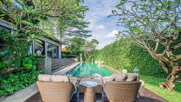 A poolside area with wicker furniture and a view of the pool. - De Prestigio Villa I (Canggu)