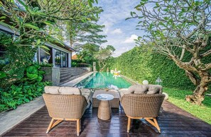 A poolside area with wicker furniture and a view of the pool. - De Prestigio Villa I (Canggu)