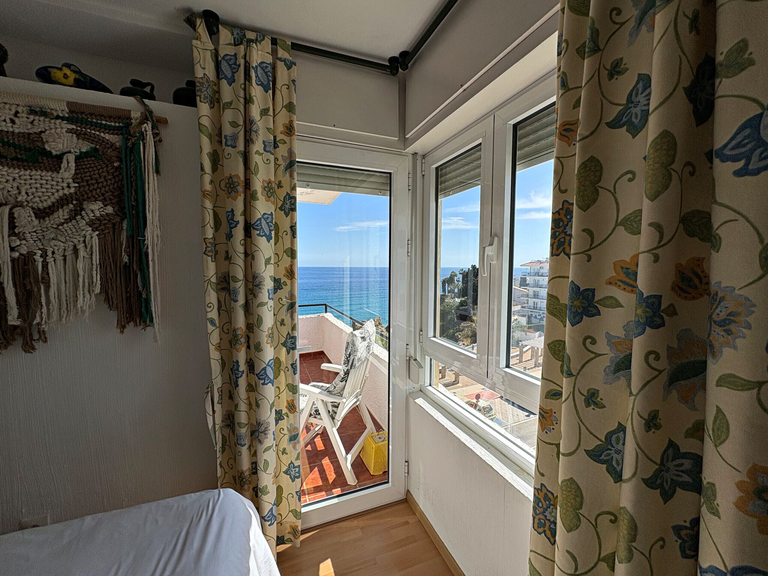 Ein Zimmer mit Bett, Meerblick und einem Balkon mit Stuhl.