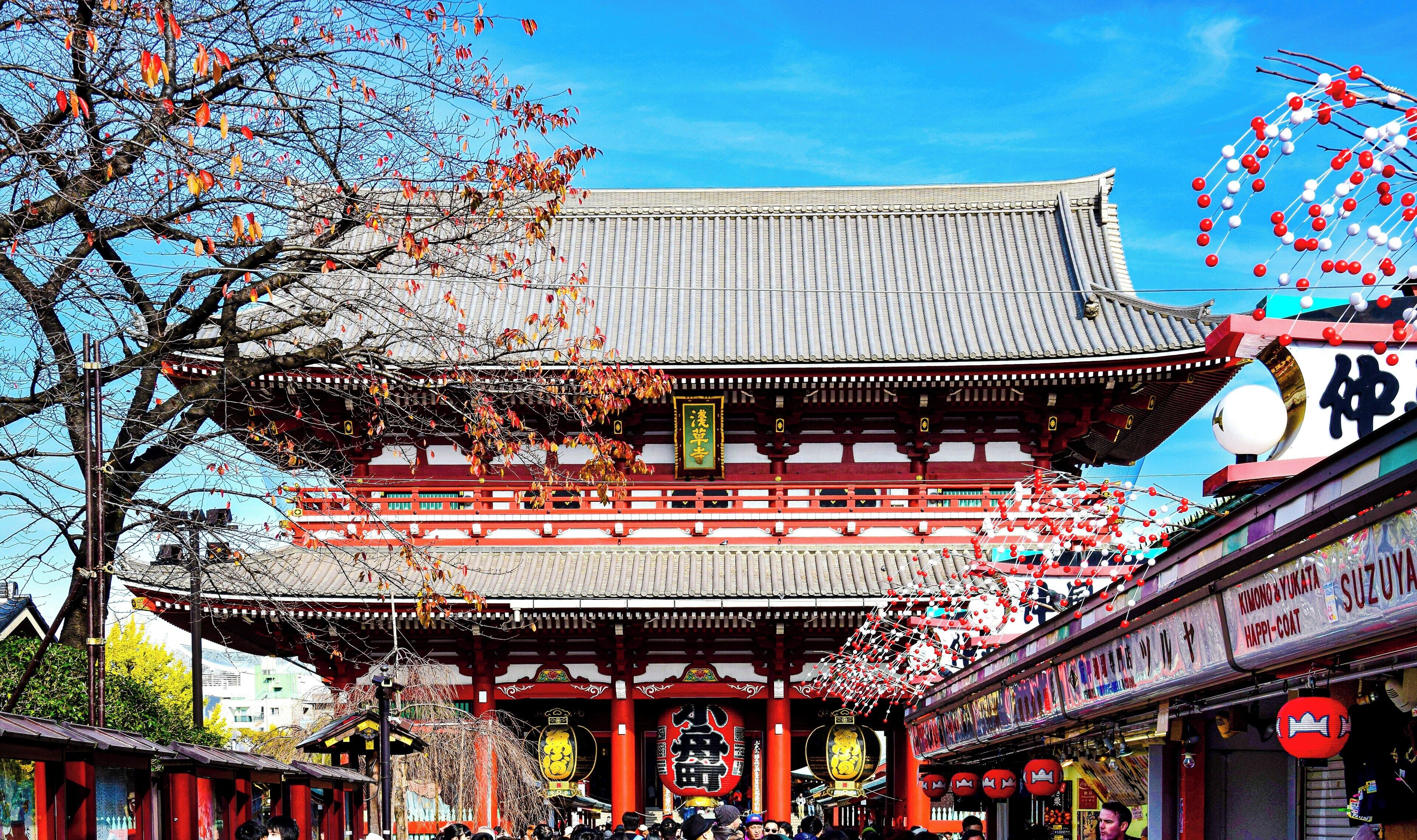 A traditional Japanese building with a tiled roof and red pillars.