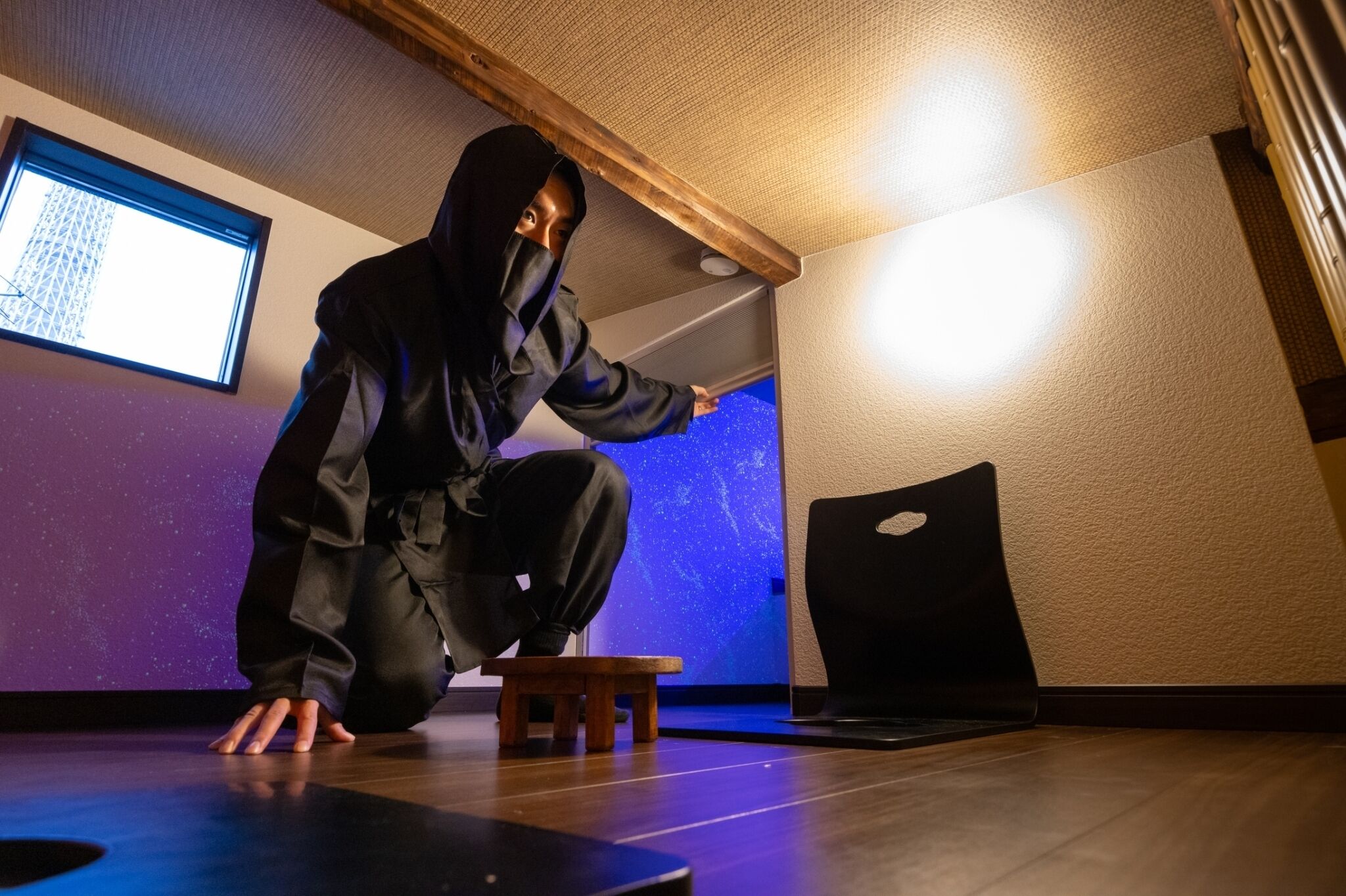 A person crouching on a wooden floor with a projector screen displaying a starry sky in the background.