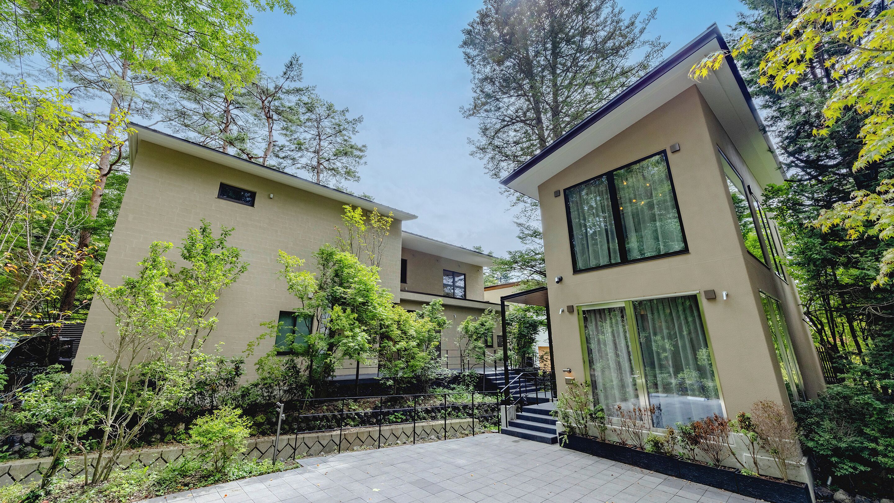 A modern building with a flat roof, large windows, and a covered outdoor area with steps leading up to the entrance.