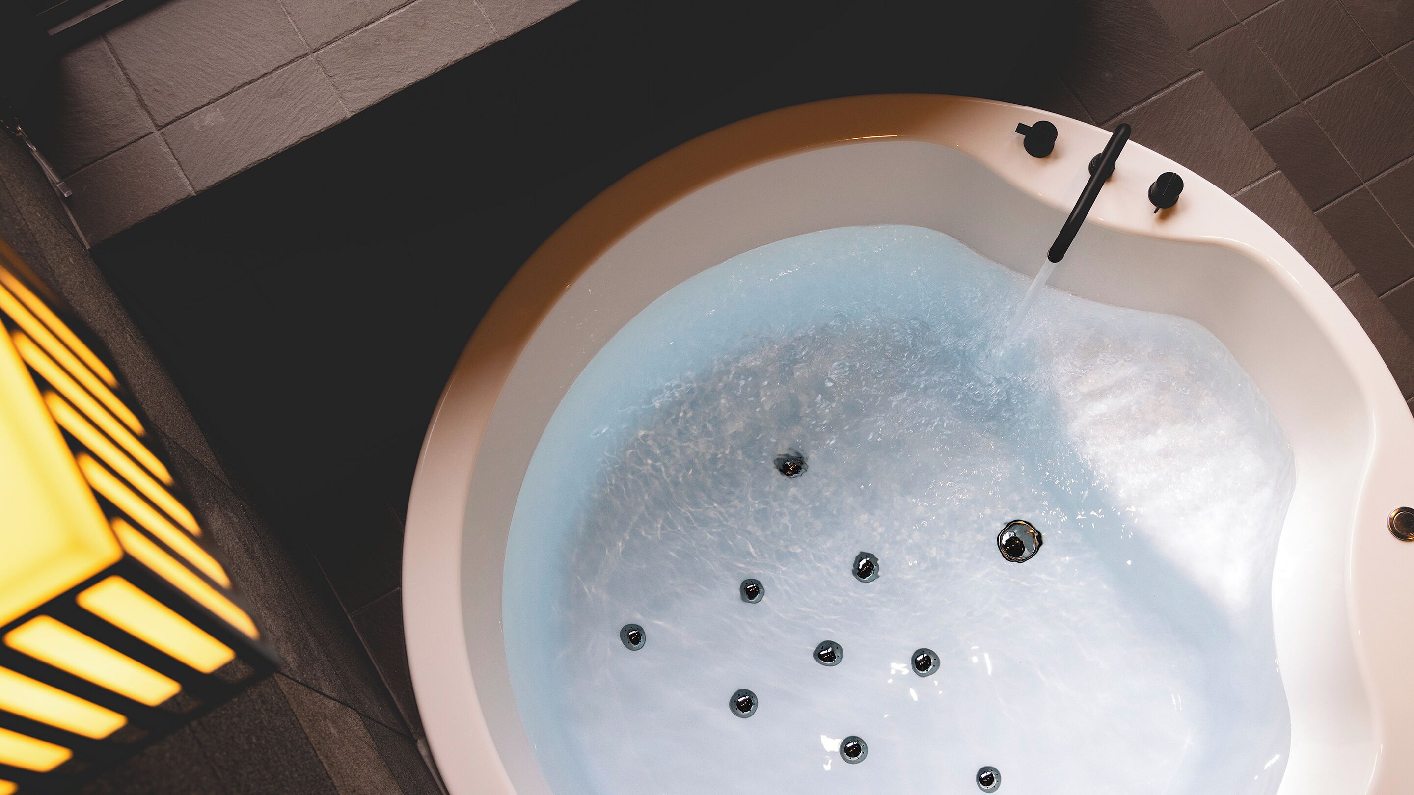 Una bañera con hidromasaje y cabezal de ducha manual.