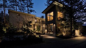 A modern two-story house with a large glass window and a stone wall. - GLAMDAY STYLE HOTEL SUITE KAWANONE (Karuizawa)