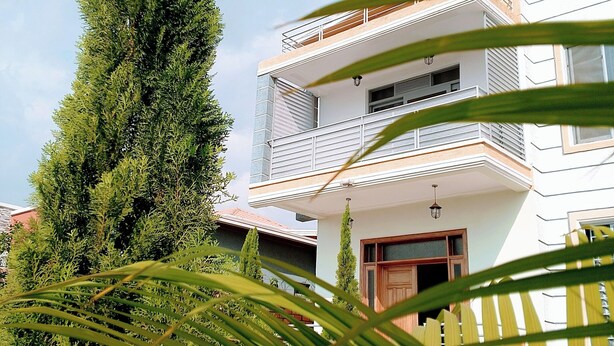 A modern two-story house with a balcony, surrounded by lush greenery and a well-maintained garden. - Kigali view Garden apart (Kigali)