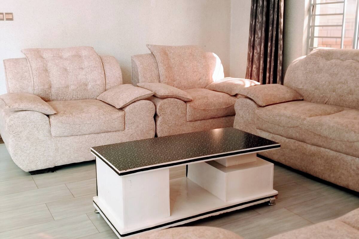 A living room with two beige sofas, a coffee table, and a window with curtains.