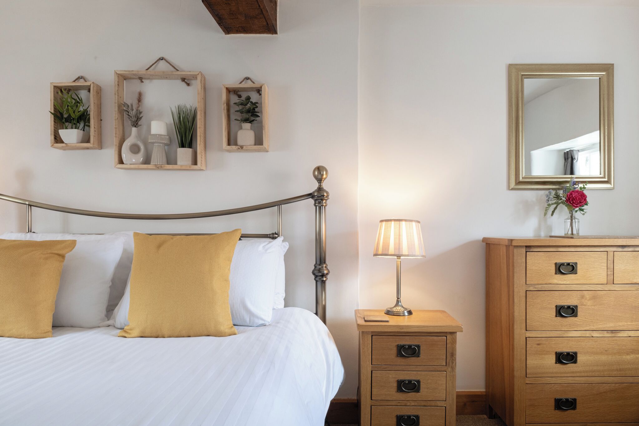 Un dormitorio ordenado con cama, mesita de noche, cómoda y decoración en la pared.