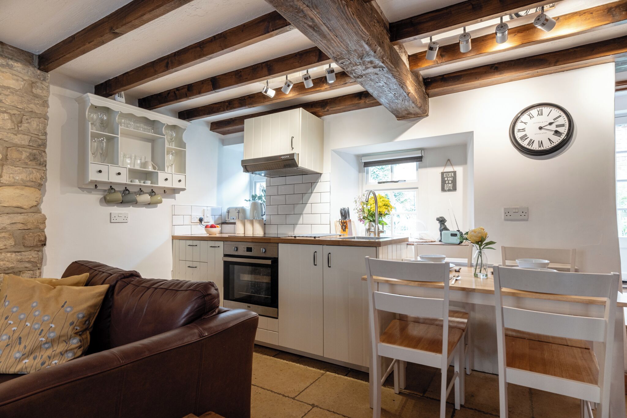 A cozy kitchen with white cabinets, a built-in oven, and a wooden ceiling.