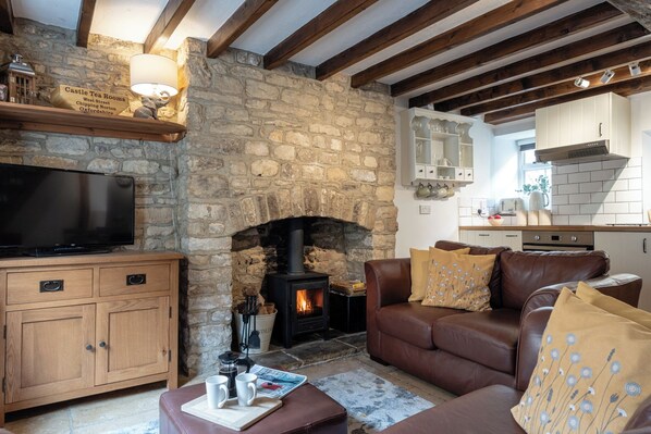 A cozy living room with a stone fireplace, a television, and a leather sofa. - Maple Cottage - Beautiful 2BD Retreat (Chipping Norton)