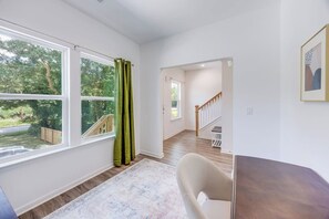 A room with a large window, a staircase, and a view of a deck.