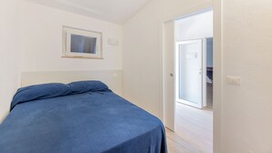 Un dormitorio con una cama, una ventana y una puerta que da a otra habitación.