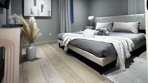 A modern bedroom with a bed, bedside tables, a desk, and a large abstract painting on the wall.
