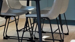 A modern dining area with a round table, four chairs, and a vase with green plants.