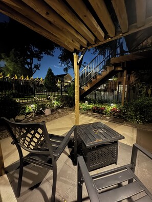 An outdoor patio with wooden furniture, a staircase, and a garden.