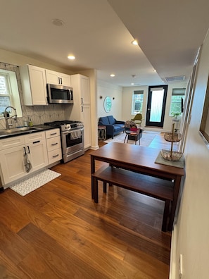 Een moderne keuken met witte kasten, roestvrijstalen apparatuur en een houten eettafel.