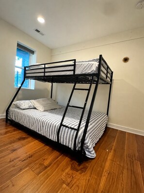 Een stapelbed met uitzicht uit het raam, houten vloeren en een plafondlamp.
