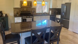 A kitchen with white cabinets, a granite countertop, a stove, a refrigerator, and pendant lights. - Private retreat with gym, hot tub, pool & playroom (Phoenix)