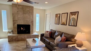 A modern living room with a fireplace, leather sofa, and a flat-screen TV. - Private retreat with gym, hot tub, pool & playroom (Phoenix)