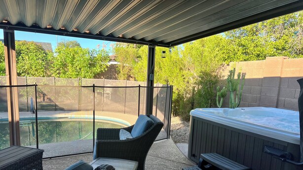 A covered patio area with a hot tub, wicker furniture, and a view of a swimming pool. - Private retreat with gym, hot tub, pool & playroom (Phoenix)