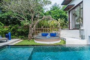 A circular outdoor seating area with a metal roof, surrounded by lush greenery and a swimming pool. - De Prestigio Villa II (Canggu)