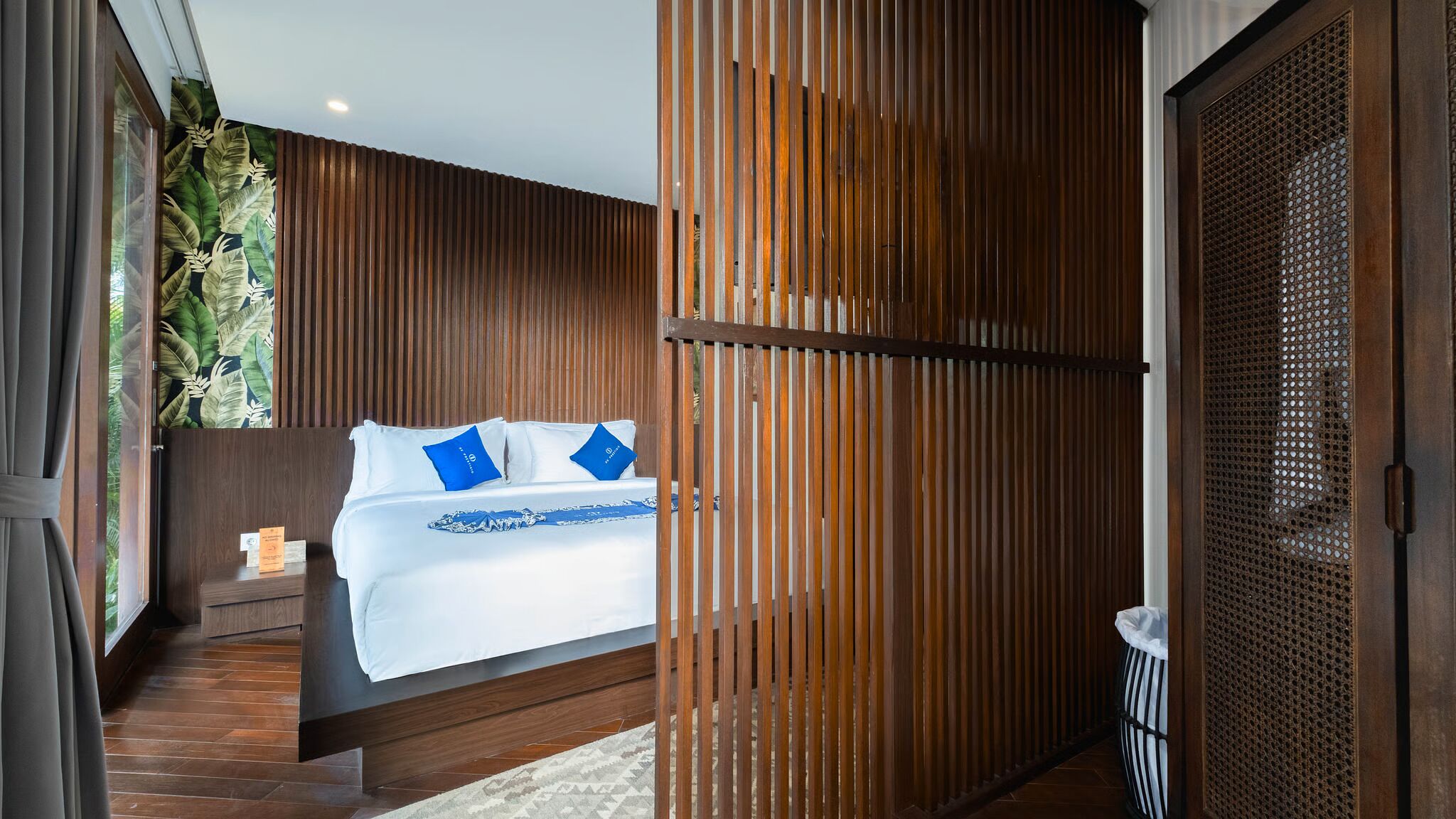 A modern bedroom with a bed, wooden paneling, and a view of the outdoors.