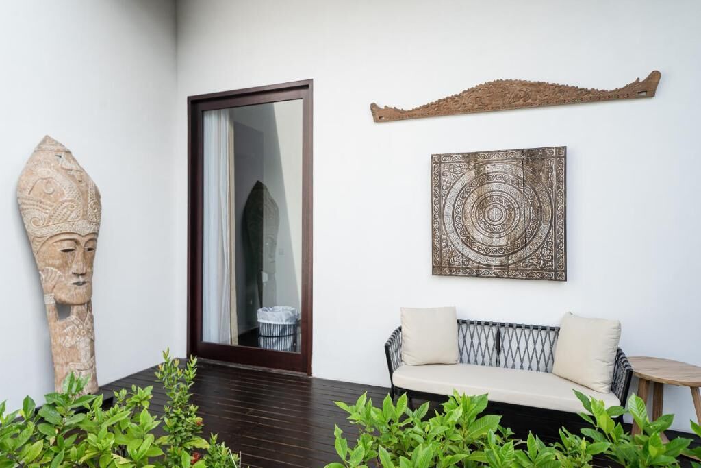A modern interior with a sofa, a decorative wall piece, and a stone sculpture.