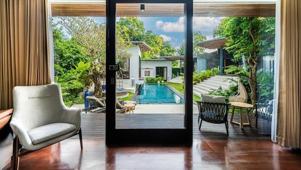 A modern interior with a view of a swimming pool and garden. - De Prestigio Villa II (Canggu)