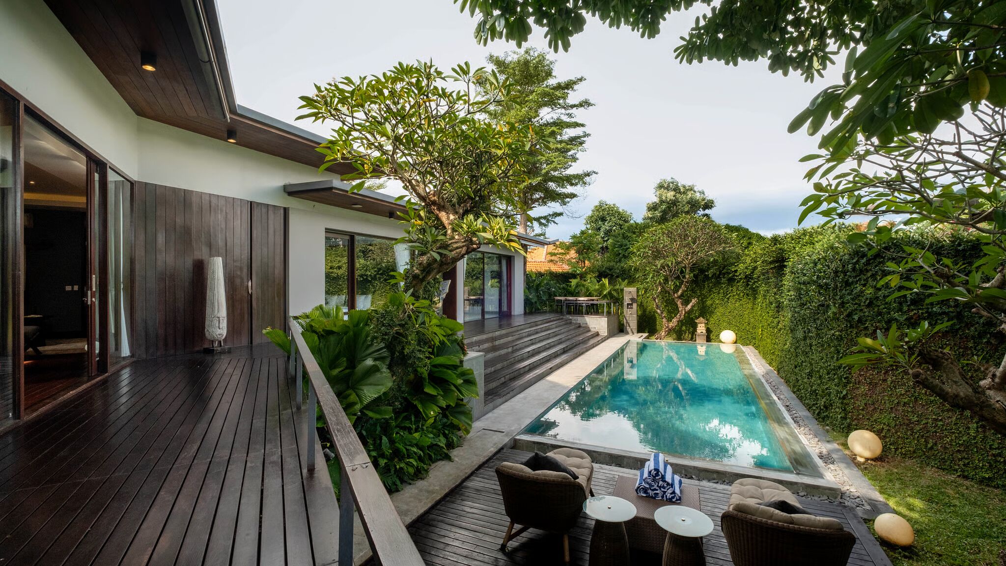 Une maison moderne dotée d’une piscine, de mobilier d’extérieur et d’une végétation luxuriante.