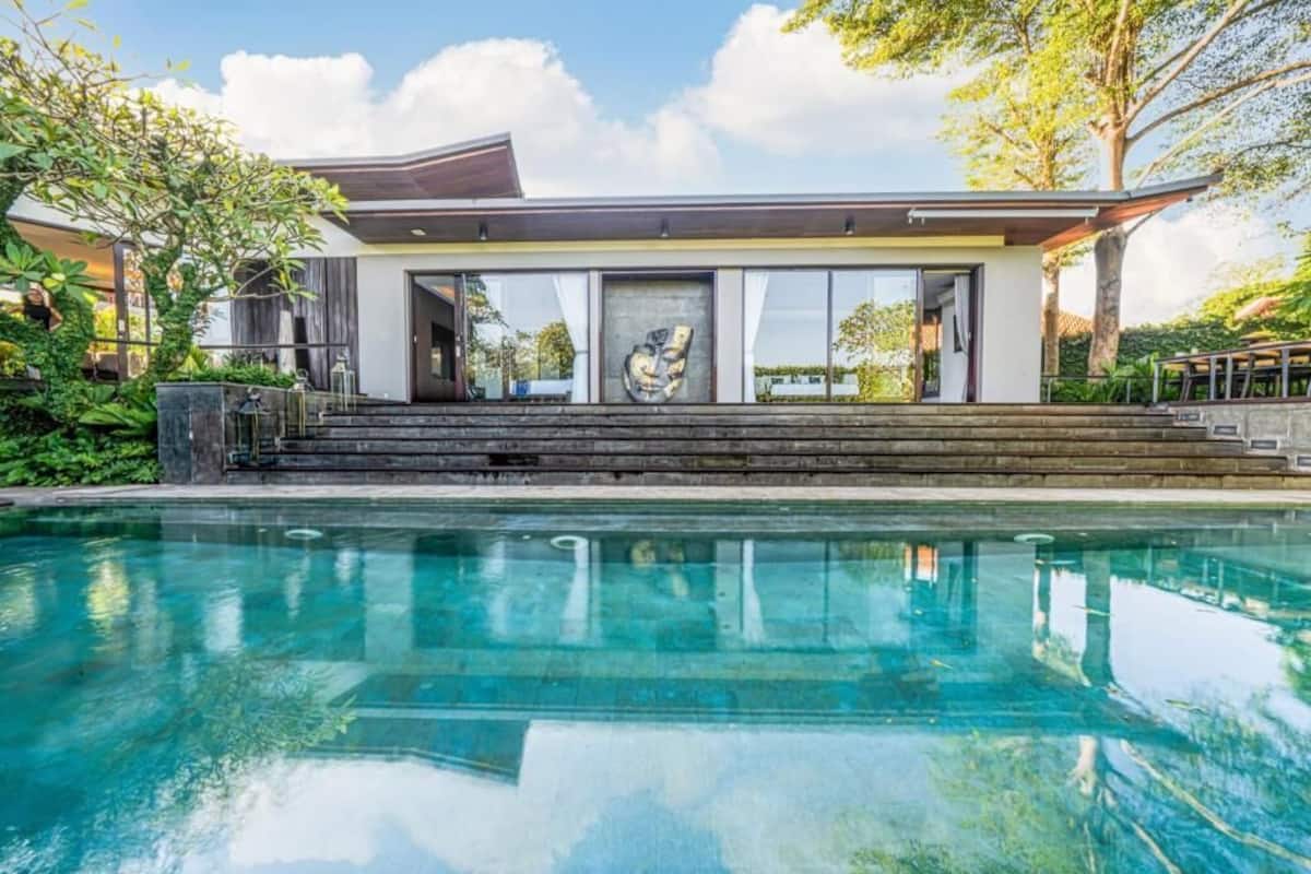 A modern house with a swimming pool, large windows, and a staircase leading to the entrance.