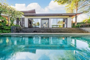 A modern house with a swimming pool, large windows, and a staircase leading to the entrance. - De Prestigio Villa II (Canggu)