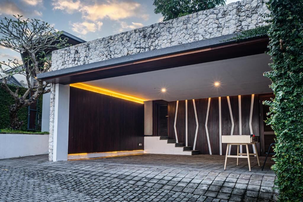 A modern house with a stone facade, a dark wooden door, and a staircase leading to an upper level.
