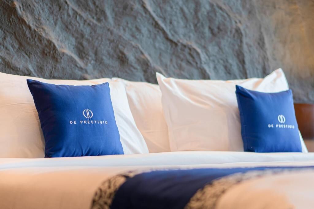 Ein Bett mit weißen und blauen Kissen, jedes mit einem Logo.