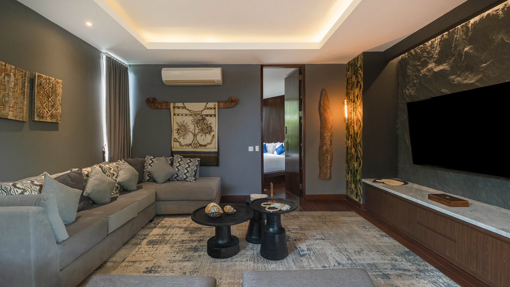 Een moderne woonkamer met een bank, salontafel, televisie en kunstwerk.