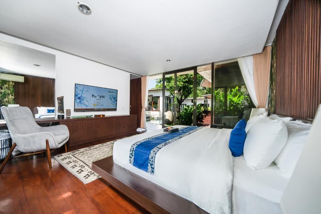 A modern bedroom with a large bed, a desk, and a TV.